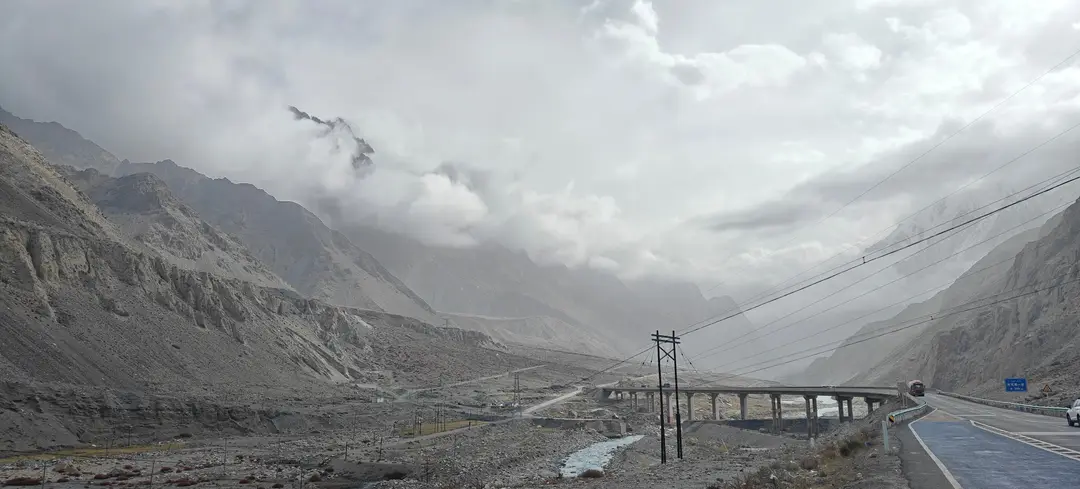 A road bridge spans the Gez River beneath peaks veiled in low cloud