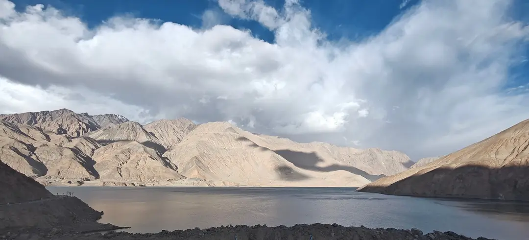 Cloud shadows fall across pale brown slopes above Bandir Blue Lake